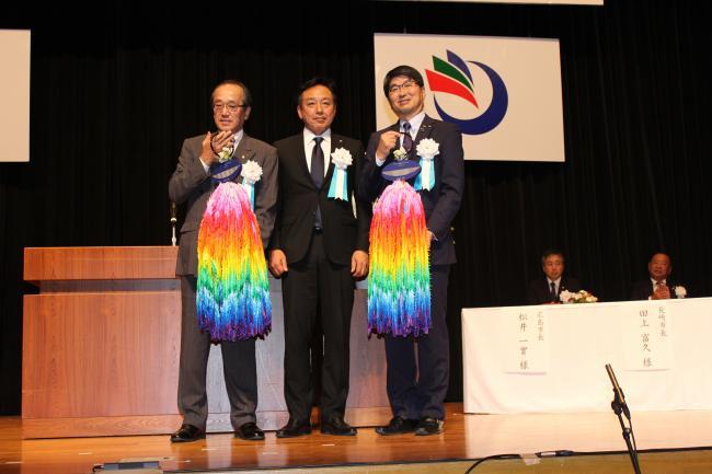 千羽鶴を持った広島市長と長崎市長の間に町長が立ってステージ上に並んでいる写真