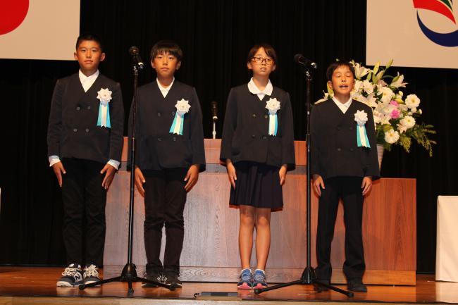 男子生徒3名と女子生徒1名がステージ上に並び平和の誓いを発表している写真