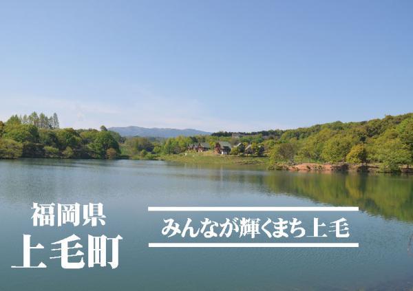 青空の下、大きな池の周りに緑が生い茂っている大池公園の写真の上に「福岡県上毛町 みんなが輝くまち上毛」と書かれている写真