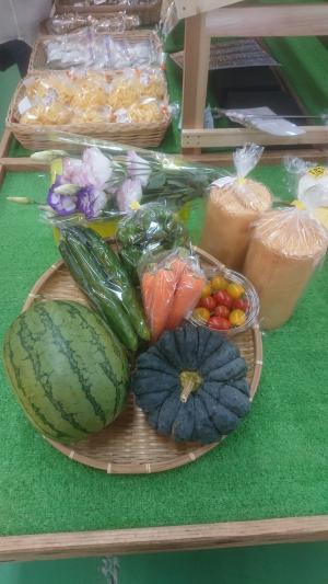 かぼちゃ、すいか、きゅうり、にんじん、プチトマトなどの野菜やお花が店内に陳列されている写真